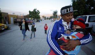 In this July 10, 2019, photo, Juan Carlos Perla carries his youngest son, Joshua Mateo Perla, as the family leaves their home in Tijuana, Mexico, for an asylum hearing in San Diego. They were among the first sent back to Mexico under a Trump administration policy that dramatically reshaped the scene at the U.S.-Mexico border by returning migrants to Mexico to wait out their U.S. asylum process.  (AP Photo/Gregory Bull)