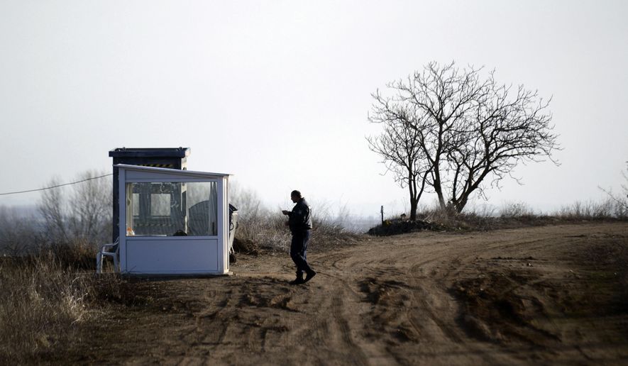 FILE - In this Friday, Feb. 24, 2017 file photo, a police officer walks outside a detention center in the northern Greek village of Fylakio, at the Greek-Turkish border. Greece is stepping up security on the land border with Turkey, through which thousands of migrants clandestinely enter Europe, with extra patrols and guards and a network of powerful surveillance cameras, officials said Friday, Jan. 31, 2020. (AP Photo/Giannis Papanikos, File)