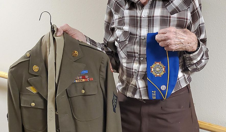 Allen Gibbs shows off his uniform from his service in the army in World War II in Rapid City, S.D.. Allen Gibbs doesn't consider himself a hero. The 98-year-old veteran has been called a hero many times in his life, but he will tell you he doesn't deserve the title compared to others he served with in World War II. (Kent Bush/Rapid City Journal via AP)
