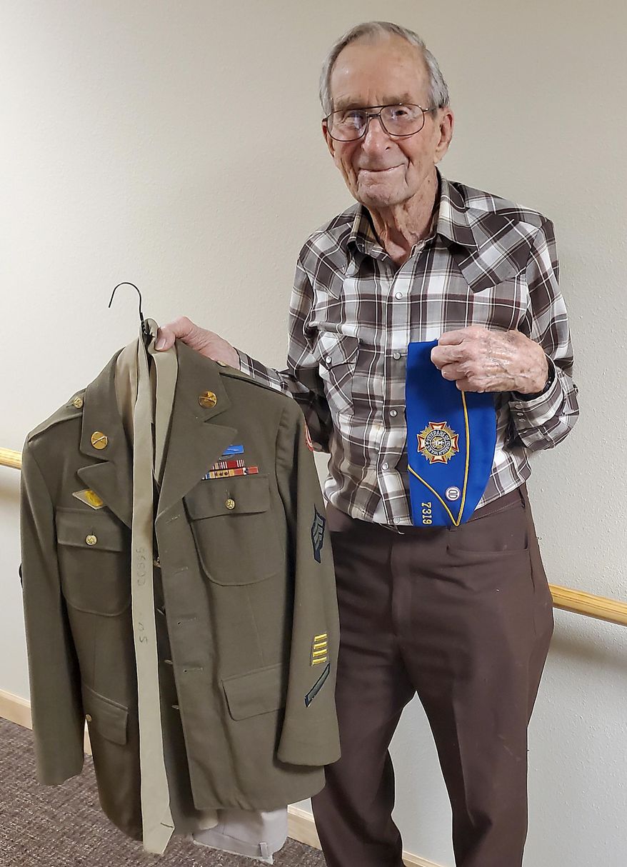 Allen Gibbs shows off his uniform from his service in the army in World War II in Rapid City, S.D.. Allen Gibbs doesn't consider himself a hero. The 98-year-old veteran has been called a hero many times in his life, but he will tell you he doesn't deserve the title compared to others he served with in World War II. (Kent Bush/Rapid City Journal via AP)