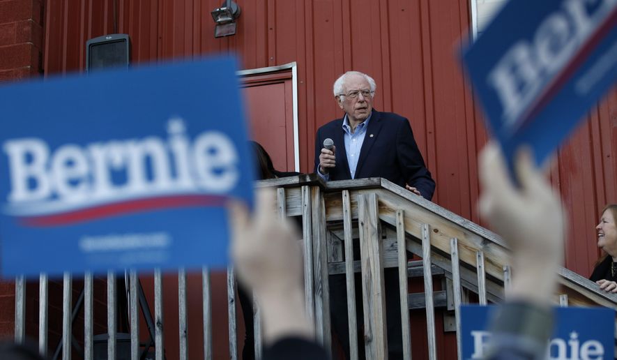 Democratic presidential candidate Sen. Bernie Sanders, I-Vt., accompanied by his wife Jane O&#39;Meara Sanders, right, speaks to an overflow crowd at a Super Bowl watch party campaign event, Sunday, Feb. 2, 2020, in Des Moines, Iowa. (AP Photo/John Locher)