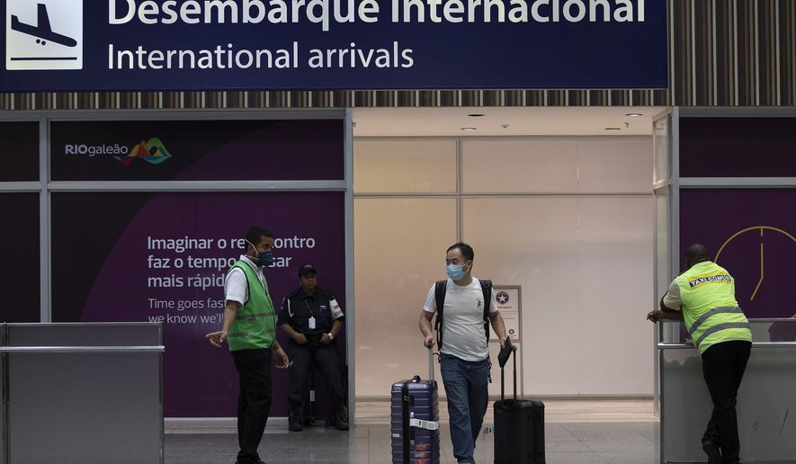 A passenger wearing a mask arrives to the Antonio Carlos Jobim Galeao International Airport, in Rio de Janeiro, Brazil, Friday, Jan. 31, 2020. Passengers and airport workers are voluntarily wearing masks as a precautionary measure amid an outbreak of the coronavirus that started in China. (AP Photo/Silvia Izquierdo)