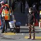 A masked worker and shopper wait for a street signal Friday, Jan. 31, 2020, in the Chinatown district in San Francisco. As China grapples with the growing coronavirus outbreak, Chinese people in California are encountering a cultural disconnect as they brace for a possible spread of the virus in their adopted homeland. (AP Photo/Ben Margot)