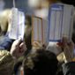 Caucus goers seated in the section for Democratic presidential candidate former Vice President Joe Biden hold up their first votes as they are counted at the Knapp Center on the Drake University campus in Des Moines, Iowa, Monday, Feb. 3, 2020. (AP Photo/Gene J. Puskar) **FILE**