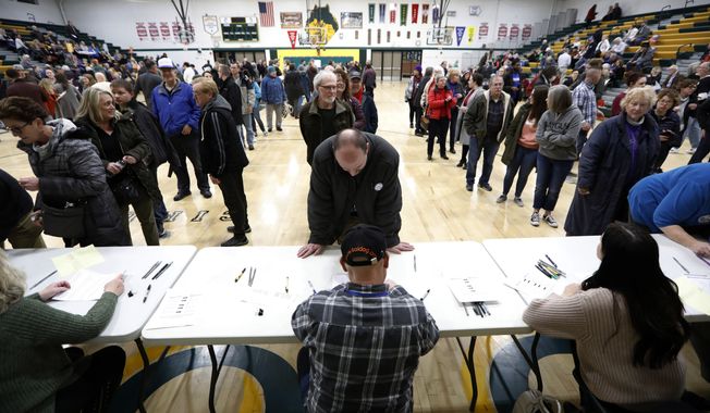Local residents check-in after arriving at an Iowa Democratic caucus at Hoover High School, Monday, Feb. 3, 2020, in Des Moines, Iowa. (AP Photo/Charlie Neibergall)