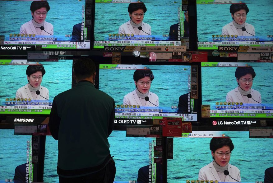 A man wears protective face masks stands in front of TV screens broadcasting Hong Kong Chief Executive Carrie Lam delivering a speech in Hong Kong, Monday, Feb. 3, 2020. Lam says the city will shut almost all land and sea border control points to the mainland from midnight to stem the spread of the novel coronavirus from China. (AP Photo/Vincent Yu)