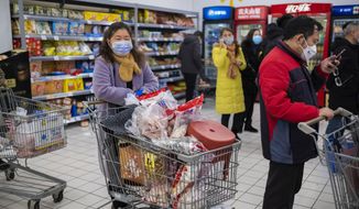 FILE - In this Jan. 22, file 2020 photo, shoppers wear face masks as they line up at a grocery store in Wuhan in central China&#39;s Hubei Province. Arek and Jenina Rataj were starting a new life in the Chinese industrial center of Wuhan when a viral outbreak spread across the city of 11 million. While they were relatively safe sheltering at home, Arek felt compelled to go out and document the outbreak of the new type of coronavirus. Among his subjects: the construction of a new hospital built in a handful of days; biosecurity check points; and empty streets. (AP Photo/Arek Rataj, File)