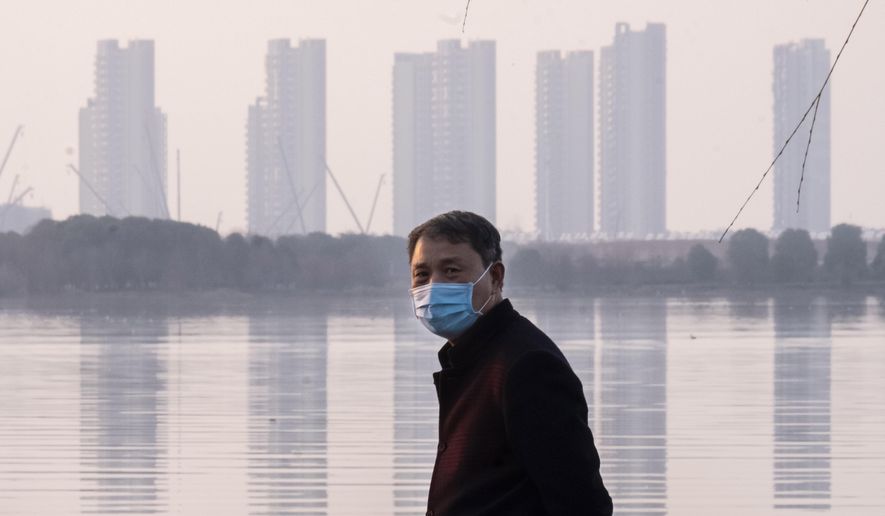 In this Jan. 30, 2020, file photo, a man wears a face mask as he stands along the waterfront in Wuhan in central China&#39;s Hubei Province. (AP Photo/Arek Rataj, File)