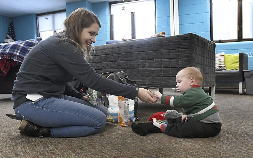 In this Wednesday, Jan. 22, 2020, photo, Kaytlin Williamson, 21, cares for her 8-month-old son, Kaeleb, at the REACH Youth Drop-in Center in Mankato, Minn. Williamson still calls the REACH her "second home" after staff there helped her find a home. (Pat Christman/The Free Press via AP)