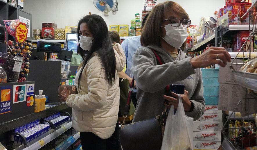 People wear protective face masks as they make purchases from a convenience store in Hong Kong, Monday, Feb, 3, 2020. Hong Kong leader Carrie Lam in a Monday press conference says the city will shut almost all land and sea border control points to the mainland from midnight to stem the spread of the novel coronavirus from China. (AP Photo/Vincent Yu)