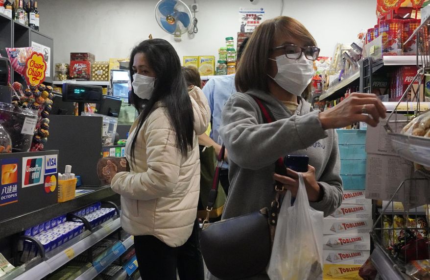 People wear protective face masks as they make purchases from a convenience store in Hong Kong, Monday, Feb, 3, 2020. Hong Kong leader Carrie Lam in a Monday press conference says the city will shut almost all land and sea border control points to the mainland from midnight to stem the spread of the novel coronavirus from China. (AP Photo/Vincent Yu)
