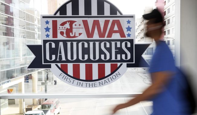 A pedestrian walks past a sign for the Iowa Caucuses on a downtown skywalk, Tuesday, Feb. 4, 2020, in Des Moines, Iowa. (AP Photo/Charlie Neibergall)