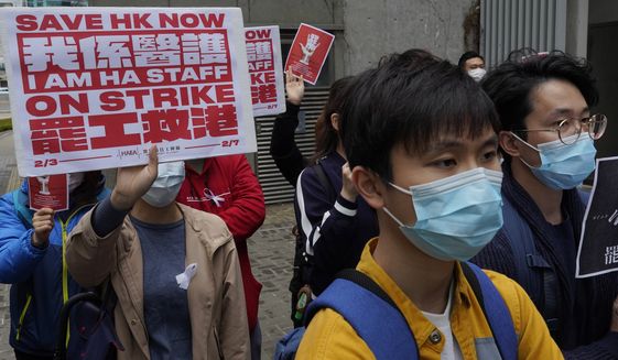 Medical staff strike over coronavirus concerns outside government headquarters in Hong Kong, Wednesday, Feb. 5, 2020. In Hong Kong, hospitals workers are striking to demand the border with mainland China be shut completely to ward off the virus, but four new cases without known travel to the mainland indicate the illness is spreading locally in the territory.(AP Photo/Vincent Yu)