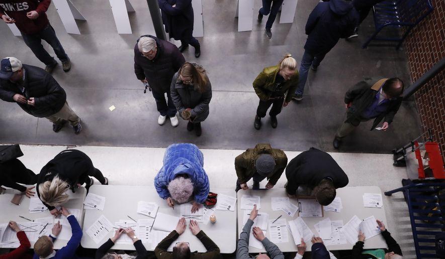 Caucus-goers check-in at a caucus at Roosevelt High School, Monday, Feb. 3, 2020, in Des Moines, Iowa. (AP Photo/Andrew Harnik)
