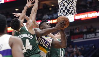New Orleans Pelicans forward Zion Williamson goes to the basket between Milwaukee Bucks forward Giannis Antetokounmpo (34) and center Brook Lopez (11) in the first half of an NBA basketball game in New Orleans, Tuesday, Feb. 4, 2020. (AP Photo/Gerald Herbert)