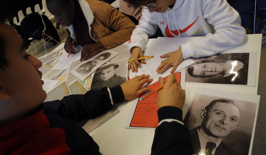 In this photo taken on Thursday Jan. 30, 2020, students work on deportees files during a workshop dedicated to the Holocaust remembrance at the Drancy Shoah memorial, outside Paris. A French Holocaust survivor Victor Perahia was 9 when his family was seized by the Nazis, and couldn't bear to speak about what happened for 40-years, but is now telling his story to schoolchildren at Drancy, backdropped by the buildings that once imprisoned him. (AP Photo/Christophe Ena)