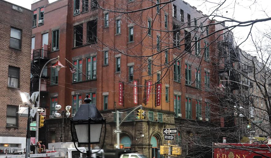 FILE In this Jan. 25, 2020 file photo, fire department officials remain on the scene in the aftermath of a fire that blazed through a building, center, that house several nonprofits and a senior center in the Chinatown section of New York. A volunteer team of conservators is working to salvage some of the 85,000 artifacts feared lost in the building fire. About a third of the collection belonging to the Museum of Chinese in America has been removed after fire and building officials deemed some areas of the structure safe, the New York Daily News reported Tuesday, Feb. 4. (AP Photo/Bebeto Matthews, File)