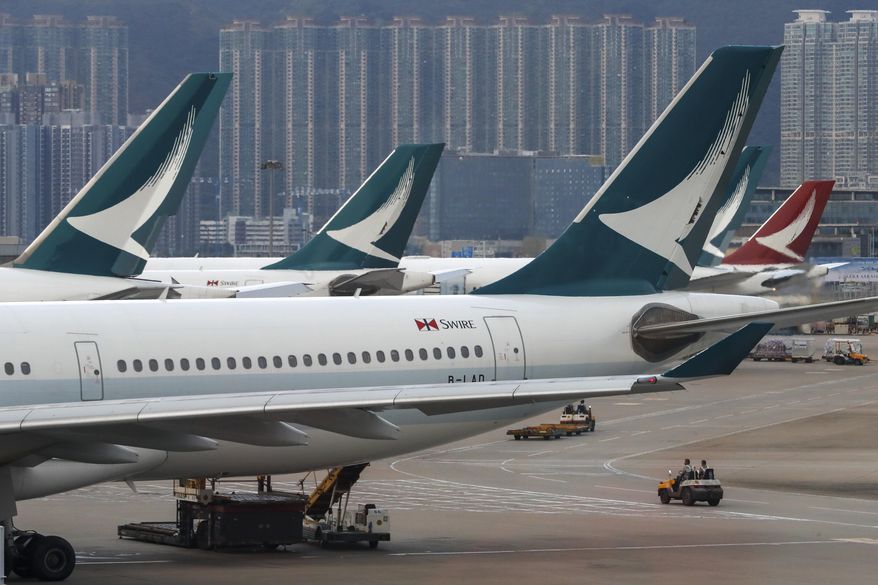 FILE - In this Aug. 12, 2019, file photo, ground crew drive past Cathay Pacific Airways planes park at the Hong Kong International Airport. Hong Kong airline Cathay Pacific Airways is asking its 27,000 employees to take three weeks of unpaid leave while the Hong Kong carrier struggles with plunging revenue due to China's virus outbreak. (AP Photo/Vincent Thian, File)