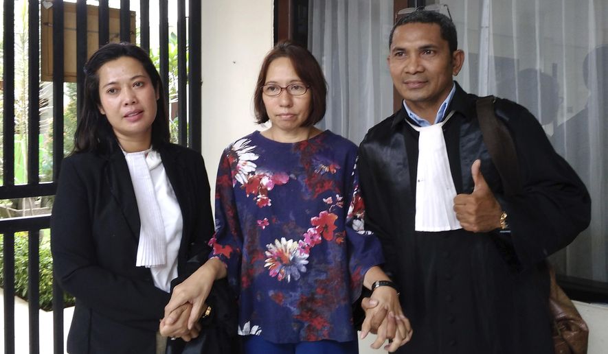 Suzethe Margareth, center, poses with her lawyers after her verdict at the Cibinong District Court in West Java, Indonesia, Wednesday, Feb. 5, 2020. Doctors say Marageth should receive psychiatric treatment as she is acquitted of blasphemy charges after taking a dog into a mosque. (AP Photo)
