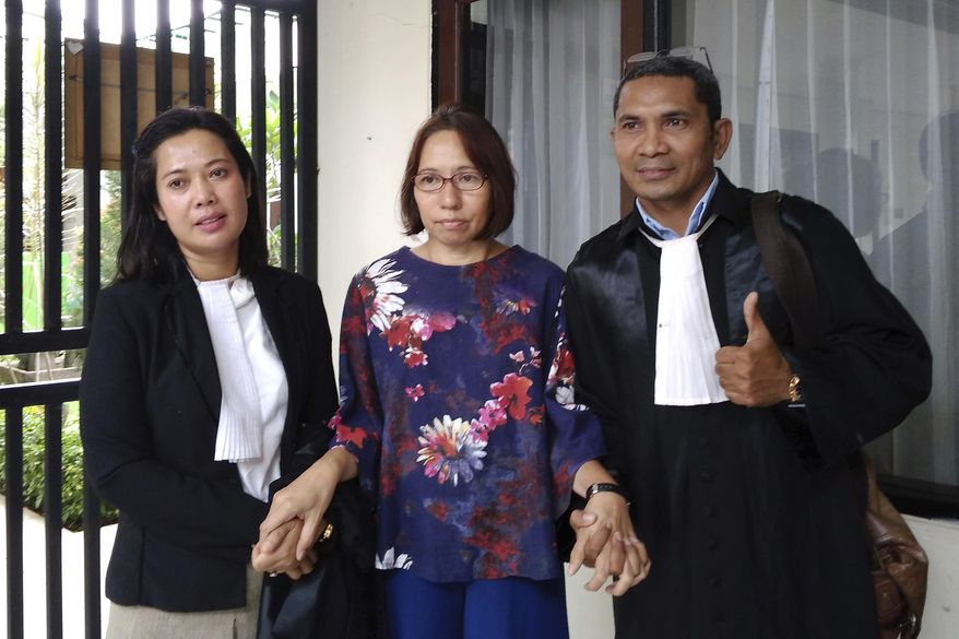 Suzethe Margareth, center, poses with her lawyers after her verdict at the Cibinong District Court in West Java, Indonesia, Wednesday, Feb. 5, 2020. Doctors say Marageth should receive psychiatric treatment as she is acquitted of blasphemy charges after taking a dog into a mosque. (AP Photo)