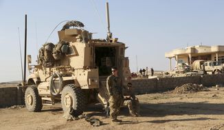 In this Feb. 23, 2017, photo, U.S. Army soldiers stand outside their armored vehicle on a joint base with the Iraqi army, south of Mosul, Iraq. (AP Photo/ Khalid Mohammed) **FILE**