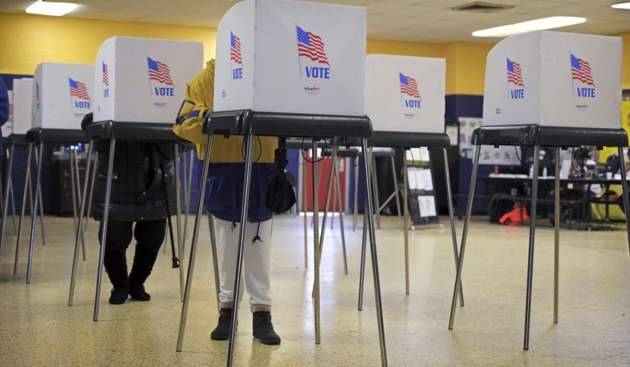 In this file photo, two voters cast ballots at School No. 122 Samuel Coleridge-Taylor for the open seat once occupied by U.S. Rep. Elijah Cummings, Tuesday, Feb. 4, 2020, in Baltimore. On March 17, 2020, Gov. Larry Hogan announced the state's April 28 congressional and presidential primary elections were being postponed to June 2. The April 28 special election for the Cummings House seat, however, will go on as planned, but be conducted solely by mail-in ballot. (Karl Merton Ferron/The Baltimore Sun via AP) **FILE**