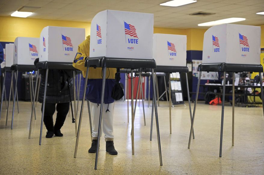 In this file photo, two voters cast ballots at School No. 122 Samuel Coleridge-Taylor for the open seat once occupied by U.S. Rep. Elijah Cummings, Tuesday, Feb. 4, 2020, in Baltimore. On March 17, 2020, Gov. Larry Hogan announced the state's April 28 congressional and presidential primary elections were being postponed to June 2. The April 28 special election for the Cummings House seat, however, will go on as planned, but be conducted solely by mail-in ballot. (Karl Merton Ferron/The Baltimore Sun via AP) **FILE**