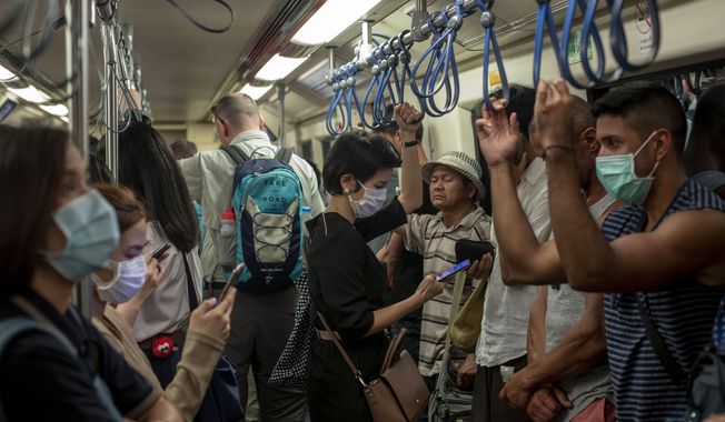 Commuters wear face masks to protect themselves from air pollution and the coronavirus on the BTS metro train in Bangkok, Thailand, Wednesday, Feb. 5, 2020. (AP Photo/Gemunu Amarasinghe)