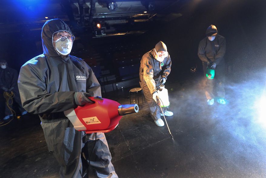 Workers wearing protective gear spray disinfectant as a precaution against a new coronavirus at a theater in Seoul, South Korea, on Thursday. More than two dozen U.S. forces and other deployed Americans are quarantined over virus exposure concerns. (ASSOCIATED PRESS)