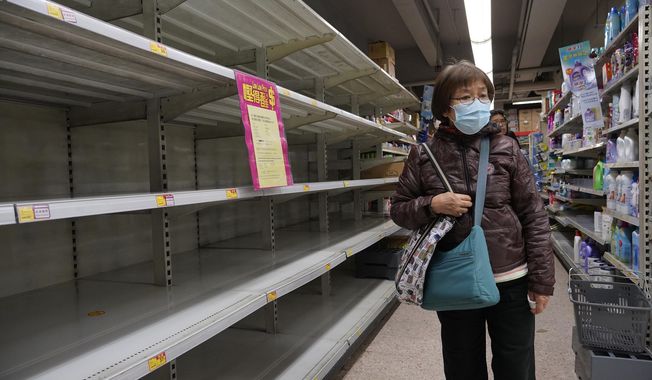 A woman wearing face mask walks past empty shelf of tissue papers at supermarket in Hong Kong, Thursday, Feb. 6, 2020. Ten more people were sickened with a new virus aboard one of two quarantined cruise ships with some 5,400 passengers and crew aboard, health officials in Japan said Thursday, as China reported 73 more deaths and announced that the first group of patients were expected to start taking a new antiviral drug. (AP Photo/Vincent Yu)