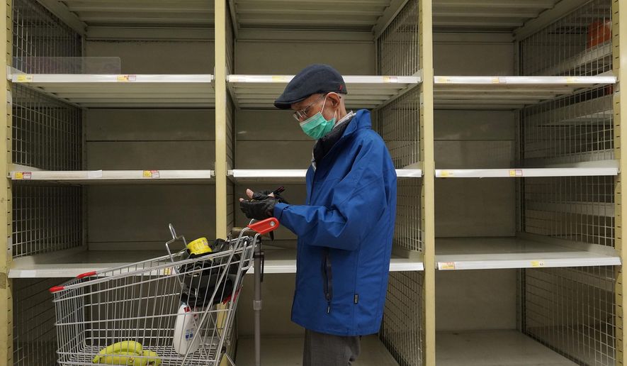 A man wearing face mask stands near an empty shelf of rice at a supermarket in Hong Kong, Thursday, Feb. 6, 2020. Ten more people were sickened with a new virus aboard one of two quarantined cruise ships with some 5,400 passengers and crew aboard, health officials in Japan said Thursday, as China reported 73 more deaths and announced that the first group of patients were expected to start taking a new antiviral drug. (AP Photo/Vincent Yu)