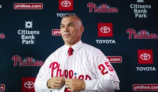 FILE - In this Oct. 28, 2019, file photo, the Philadelphia Phillies&#39; new manager, Joe Girardi puts on his uniform during a news conference in Philadelphia. The Phillies enter spring training with a new manager who has a winning pedigree. Girardi, who led the Yankees to a World Series title, takes over in Philadelphia while righty Zack Wheeler and shortstop Didi Gregorious were the biggest on-field additions.  (AP Photo/Matt Rourke, File)