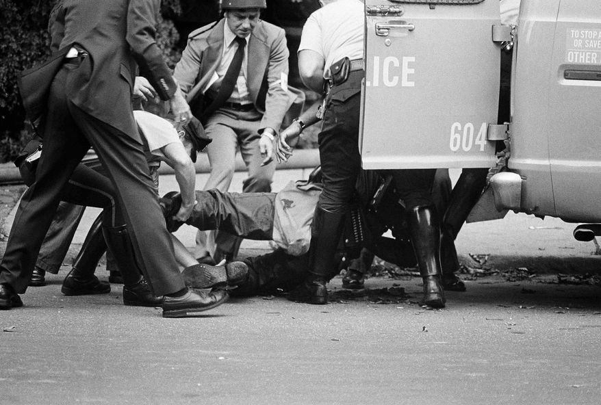 FILE—In this file photo from August 8, 1978, gunshot victim James Ramp is lifted into police van after he was shot during confrontation with the group MOVE in Philadelphia's west side. Ramp was killed and at least 10 other persons were injured in a shootout. An attorney for Chuck Sims Africa, who was one of the MOVE group members convicted of third-degree murder in the 1978 shooting death of Officer Ramp, posted on Twitter that the man had been released from a Pennsylvania prison. Africa was the last of the so-called MOVE 9 to be paroled. Attorney Brad Thomson confirmed via email that Africa had been released Friday, Feb. 7, 2020. (AP Photo/Paul Shane, File)