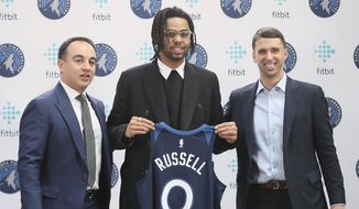 New Minnesota Timberwolves NBA basketball player D&#x27;Angelo Russell, center, holds his new jersey between President of Basketball Operations Gersson Rosas, left, and head coach Ryan Saunders during his introduction to the media, Friday, Feb. 7, 2020, in Minneapolis, following a trade that sent Timberwolves&#x27; Andrew Wiggins to the Golden State Warriors. (AP Photo/Jim Mone)