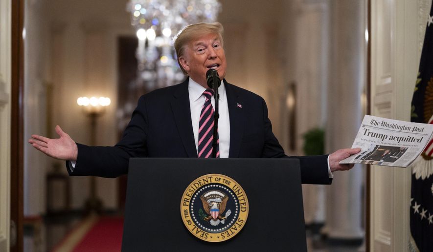 President Donald Trump holds up a newspaper tat reads "Trump acquitted" during during an event celebrating his impeachment acquittal, in the East Room of the White House, Thursday, Feb. 6, 2020, in Washington. (AP Photo/Evan Vucci)