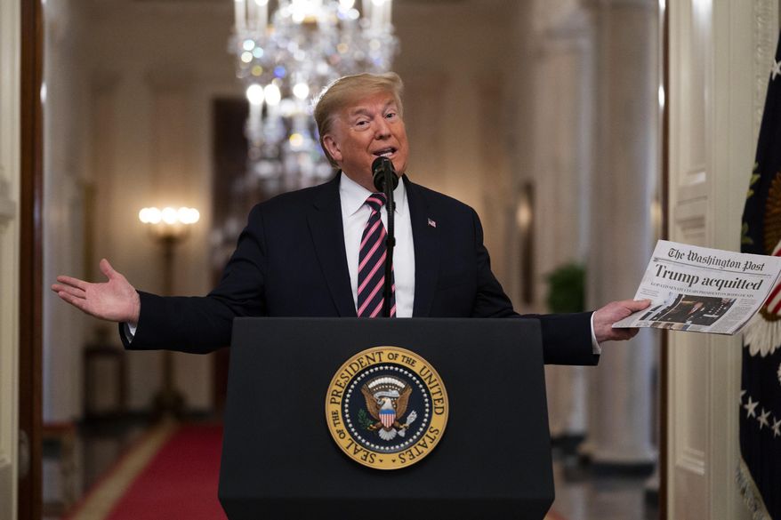 President Donald Trump holds up a newspaper tat reads "Trump acquitted" during during an event celebrating his impeachment acquittal, in the East Room of the White House, Thursday, Feb. 6, 2020, in Washington. (AP Photo/Evan Vucci)