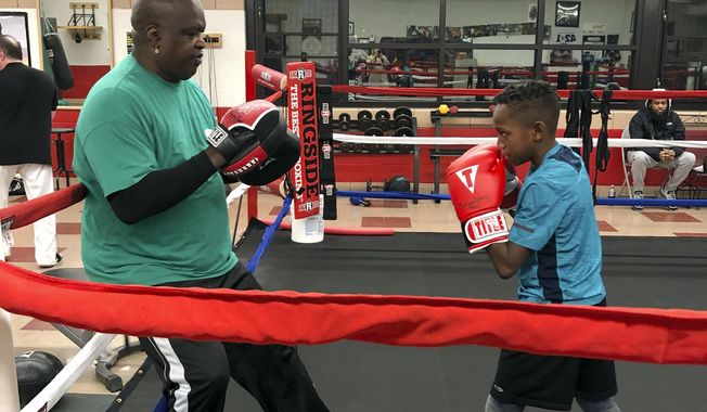 In this Tuesday, Feb. 4, 2020 photo, James &amp;quot;Buster&amp;quot; Douglas, the former world heavyweight champion, works with a student at the Thompson Community Center in Columbus, Ohio, where he teaches youth boxing. In one of the more spectacular upsets in sports history, Douglas defeated Mike Tyson, the reigning world heavyweight champion on Feb. 11, 1990, in Tokyo. (AP Photo/Julie Carr Smyth)
