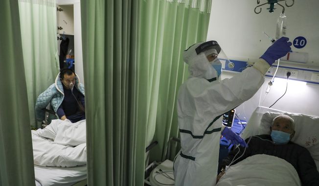In this Thursday, Feb. 6, 2020, photo, a nurse checks on a patient in the isolation ward for 2019-nCoV patients at a hospital in Wuhan in central China&#x27;s Hubei province. The number of confirmed cases of the new virus has risen again in China on Saturday, Feb. 8, 2020, as the ruling Communist Party faced anger and recriminations from the public over the death of a doctor who was threatened by police after trying to sound the alarm about the disease over a month ago. (Chinatopix via AP)