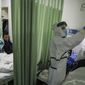 In this Thursday, Feb. 6, 2020, photo, a nurse checks on a patient in the isolation ward for 2019-nCoV patients at a hospital in Wuhan in central China&#39;s Hubei province. The number of confirmed cases of the new virus has risen again in China on Saturday, Feb. 8, 2020, as the ruling Communist Party faced anger and recriminations from the public over the death of a doctor who was threatened by police after trying to sound the alarm about the disease over a month ago. (Chinatopix via AP)