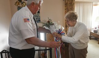 In this Jan. 24, 2020, photo, James Kuchwara, VFW Post #25 commander, gives flowers to Ann Spearmint in Scranton, Pa., to honor her brother, Staff Sgt. Joseph Eugene Prokop, who died in the waning months of World War II. Spearmint, 91, believed for more than seven decades that her brother died when Germans shot down his B-17 bomber near Frankfurt. Historians in Hanau, Germany, have recently discovered that Prokop, then 22, survived the downing of the bomber only to be captured by the Germans and summarily executed after a Gestapo officer learned one of his crewmates was Jewish. (Jason Farmer/The Times-Tribune via AP)