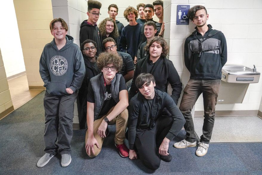 In this Thursday, Jan. 30, 2020, photo, the Men's Bathroom Choir pose for a group portrait in the entrance to the bathroom, where they practice and perform, at Gibbs High School, in St. Petersburg, Fla. The idea for Men’s Bathroom Choir was born last fall when Timofei Sennikov, front row, center, 18, thought about the nice acoustics offered by the cinder block walls. He started asking classmates to meet him there, and word spread. (Martha Asencio Rhine/Tampa Bay Times via AP)