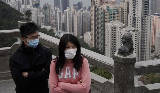 Tourists wear masks at the Peak, a popular tourist spot in Hong Kong, Sunday, Feb. 9, 2020. Health authorities are scrambling to halt the spread of a new virus that has killed hundreds in China, restricting visitors from the country and confining thousands on cruise ships for extensive screening after passengers have tested positive. (AP Photo/Kin Cheung)