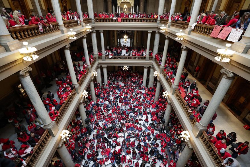 FILE - In this Nov. 19, 2019, file photo thousands of Indiana teachers wearing red hold rally at the Statehouse in Indianapolis. The Statehouse rally put complaints about their treatment squarely in front of Indiana lawmakers as this year’s legislative session was about to start. But those loud chants for improved school funding didn’t result in any additional money. (AP Photo/Michael Conroy, File)