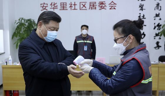 In this photo released by Xinhua News Agency, Chinese President Xi Jinping, left, wearing a protective face mask receives a temperature check as he inspects the novel coronavirus pneumonia prevention and control work at a neighbourhoods in Beijing, Monday, Feb. 10, 2020. China reported a rise in new virus cases on Monday, possibly denting optimism that its disease control measures like isolating major cities might be working, while Japan reported dozens of new cases aboard a quarantined cruise ship. (Pang Xinglei/Xinhua via AP)