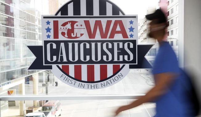 In this Feb. 4, 2020, photo, a pedestrian walks past a sign for the Iowa Caucuses on a downtown skywalk, Tuesday, Feb. 4, 2020, in Des Moines, Iowa. (AP Photo/Charlie Neibergall) ** FILE **