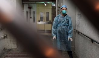 A personnel wearing protective suit waits near an entrance at the Cheung Hong Estate, a public housing estate during evacuation of residents in Hong Kong, Tuesday, Feb. 11, 2020. The Centre for Health Protection of the Department of Health evacuated some residents from the public housing estate after two cases of novel coronavirus infection to stop the potential risk of further spread of the virus. (AP Photo/Kin Cheung)