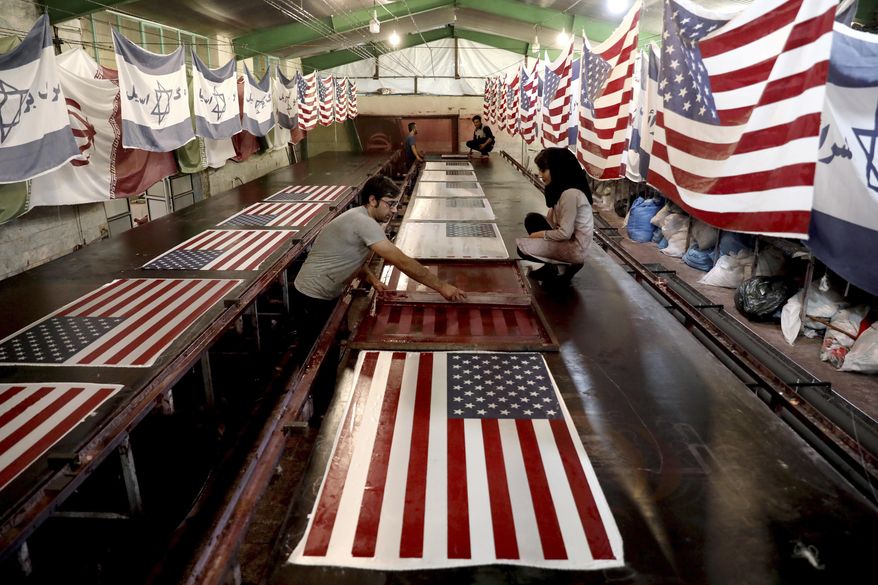 In this Saturday, Feb. 8, 2020, photo, workers print U.S. flags using a silkscreen, at the Diba Parcham Khomein factory in Heshmatieh village, a suburb of Khomein city, in central Iran. Workers at a small Iranian factory diligently add all 50 stars and 13 bars to American flags while carefully imprinting the Star of David on those of Israel. That's even as all their work is destined to go up in smoke. This factory serves as a major producer for the American and Israeli flags constantly burned at demonstrations in the Islamic Republic. (AP Photo/Ebrahim Noroozi)