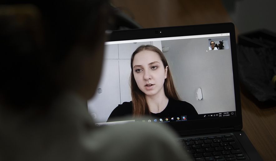 Adrielly Eger gives a video interview from the Anapolis airbase in Annapolis, Goias state, where she is in quarantine with others, as she gives an interview to the A.P. in Rio de Janeiro, Brazil, Tuesday, Feb. 11, 2020. For the next two weeks, the Brazilian model and 33 other individuals repatriated from China on Sunday will be staying at the Anapolis airbase, in the Brazilian state of Goias. (AP Photo/Silvia Izquierdo)