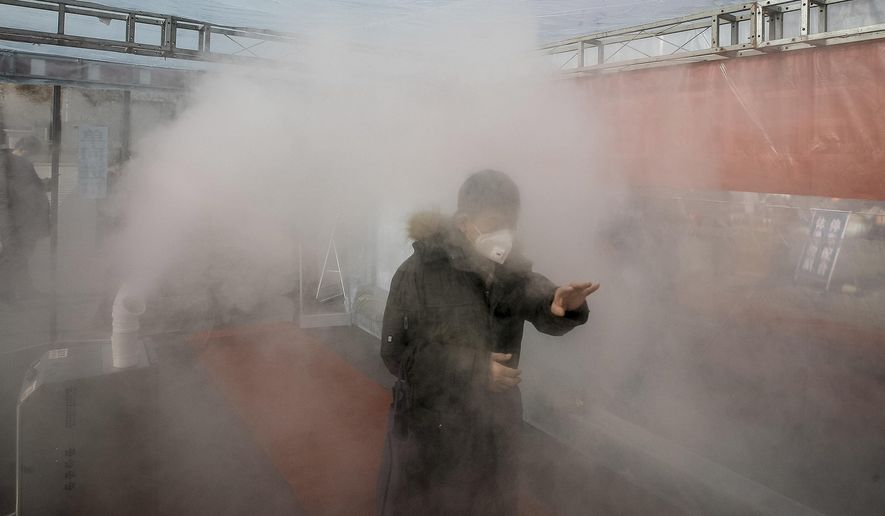 A man walks through a disinfectant spray in order to return home at a residential complex in northern China&#39;s Tianjin Municipality Tuesday, Feb. 11, 2020. China&#39;s daily death toll from a new virus topped 100 for the first time and pushed the total past 1,000 dead, authorities said Tuesday after leader Xi Jinping visited a health center to rally public morale amid little sign the contagion is abating. (Chinatopix Via AP) CHINA OUT