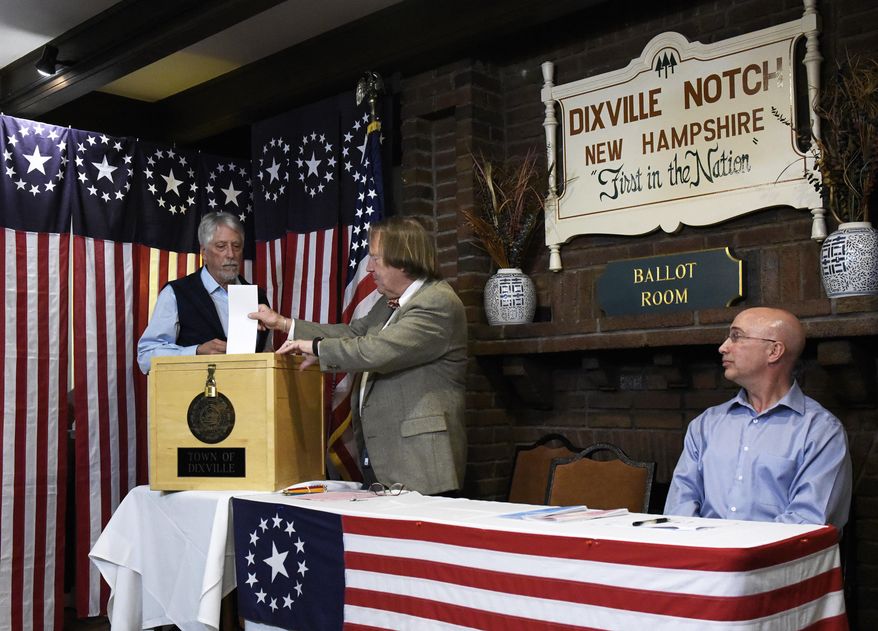 Selectman Les Otten, left, casts the first ballot of the New Hampshire presidential primary election during the midnight vote at The Balsams Resort in Dixville Notch, N.H., early Tuesday, Feb. 11, 2020. Three of the five votes went to Democratic candidate Michael Bloomberg. (Paul Hayes/Caledonian-Record via AP)